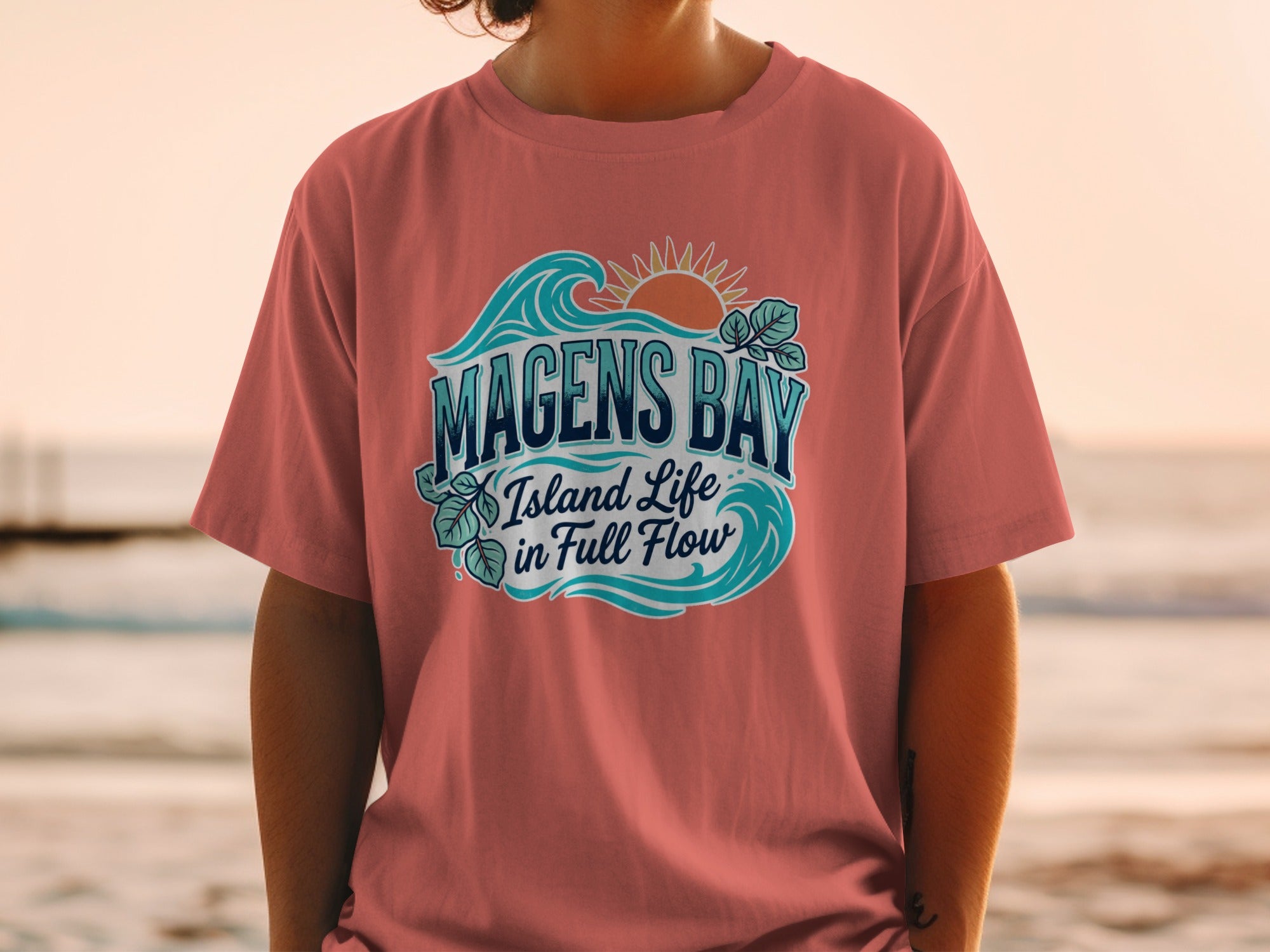 T-shirt graphic with text "Magens Bay Island Life in Full Flow" and wave, sun, and leaf design.