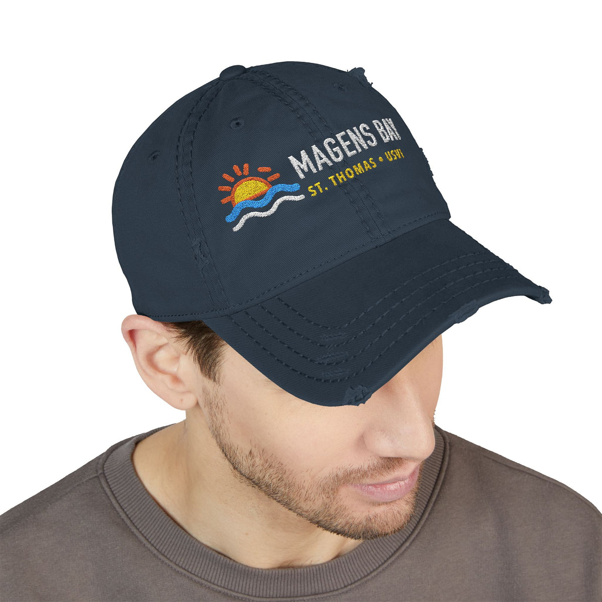 Distressed navy baseball cap with "Magens Bay, St. Thomas, USVI" text and sun and wave graphic.