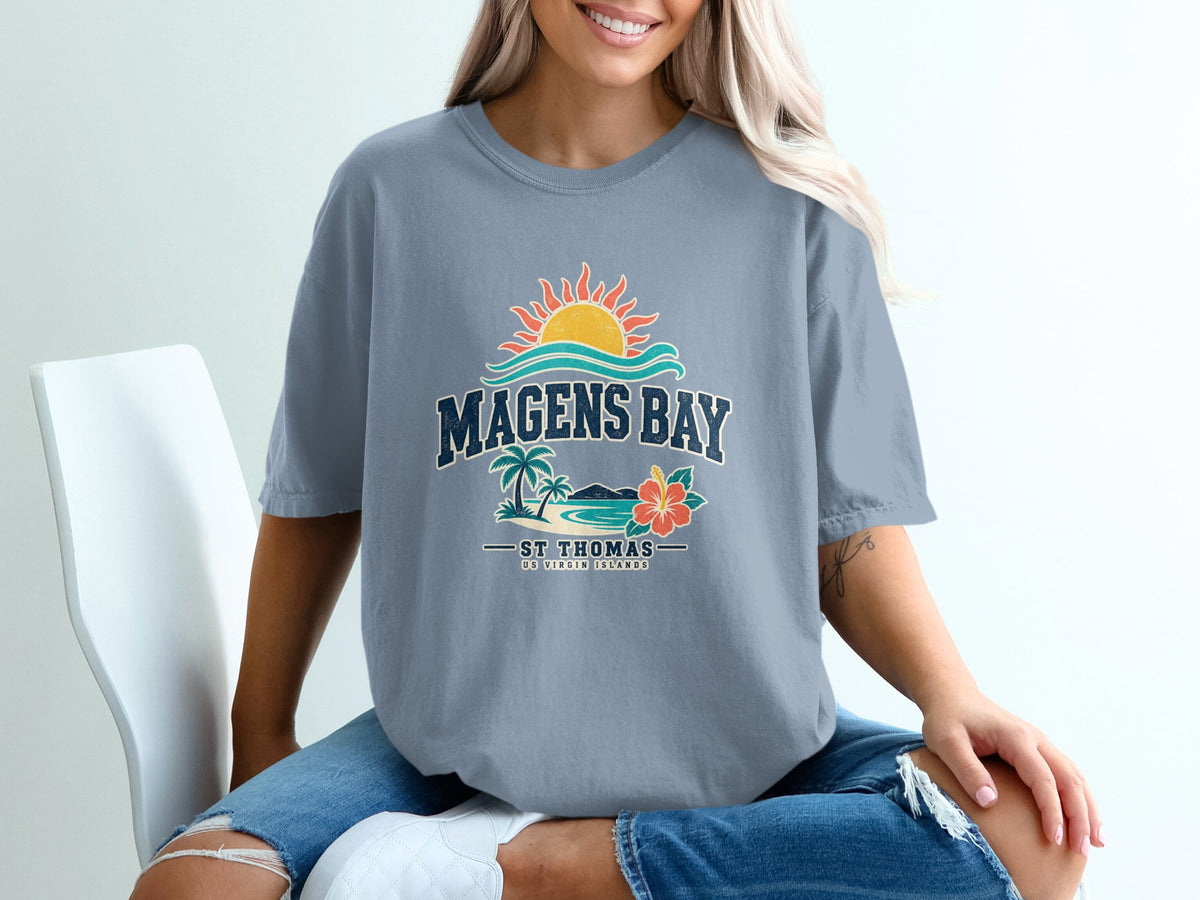A woman wearing a blue t-shirt featuring a retro Magens Bay St Thomas graphic design.