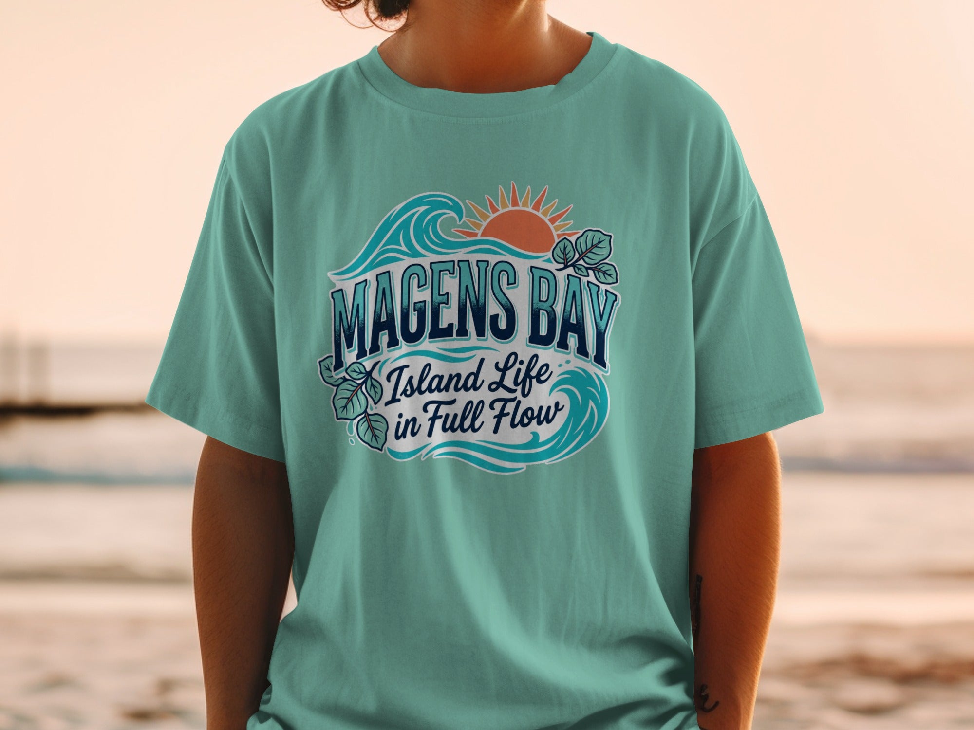 Teal t-shirt with "Magens Bay Island Life in Full Flow" text and sun/wave graphic.
