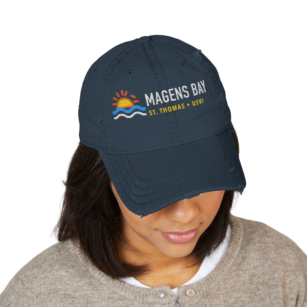 Navy distressed baseball cap with "Magens Bay St. Thomas USVI" text and sunset graphic.