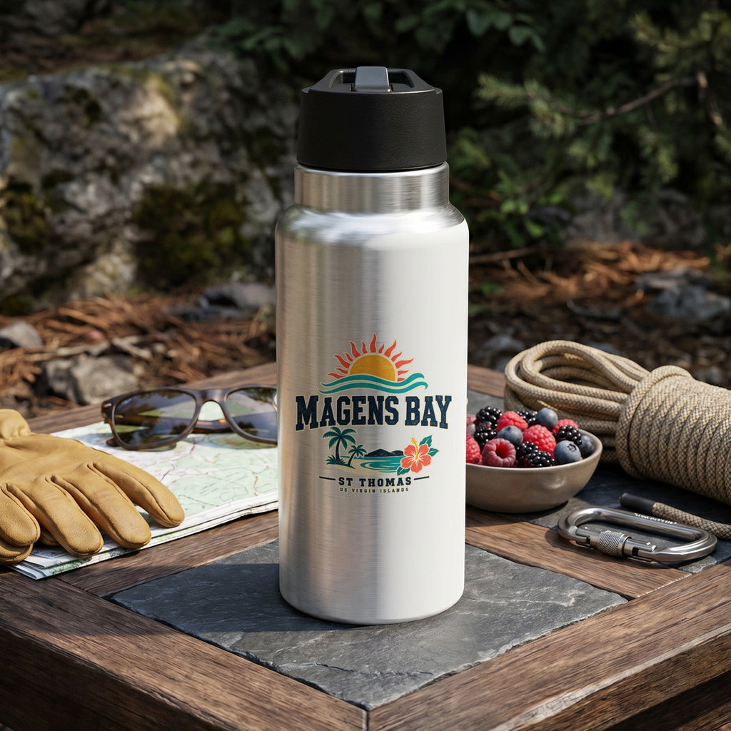 Silver insulated bottle with Magens Bay St. Thomas logo, outdoors with gear.