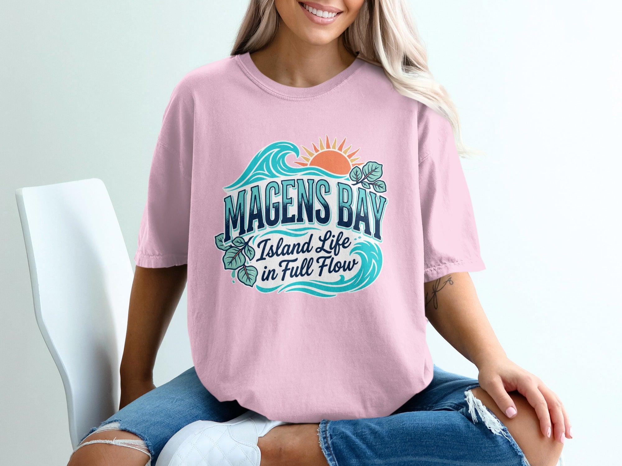 Pink t-shirt with "Magens Bay Island Life in Full Flow" ocean graphic.