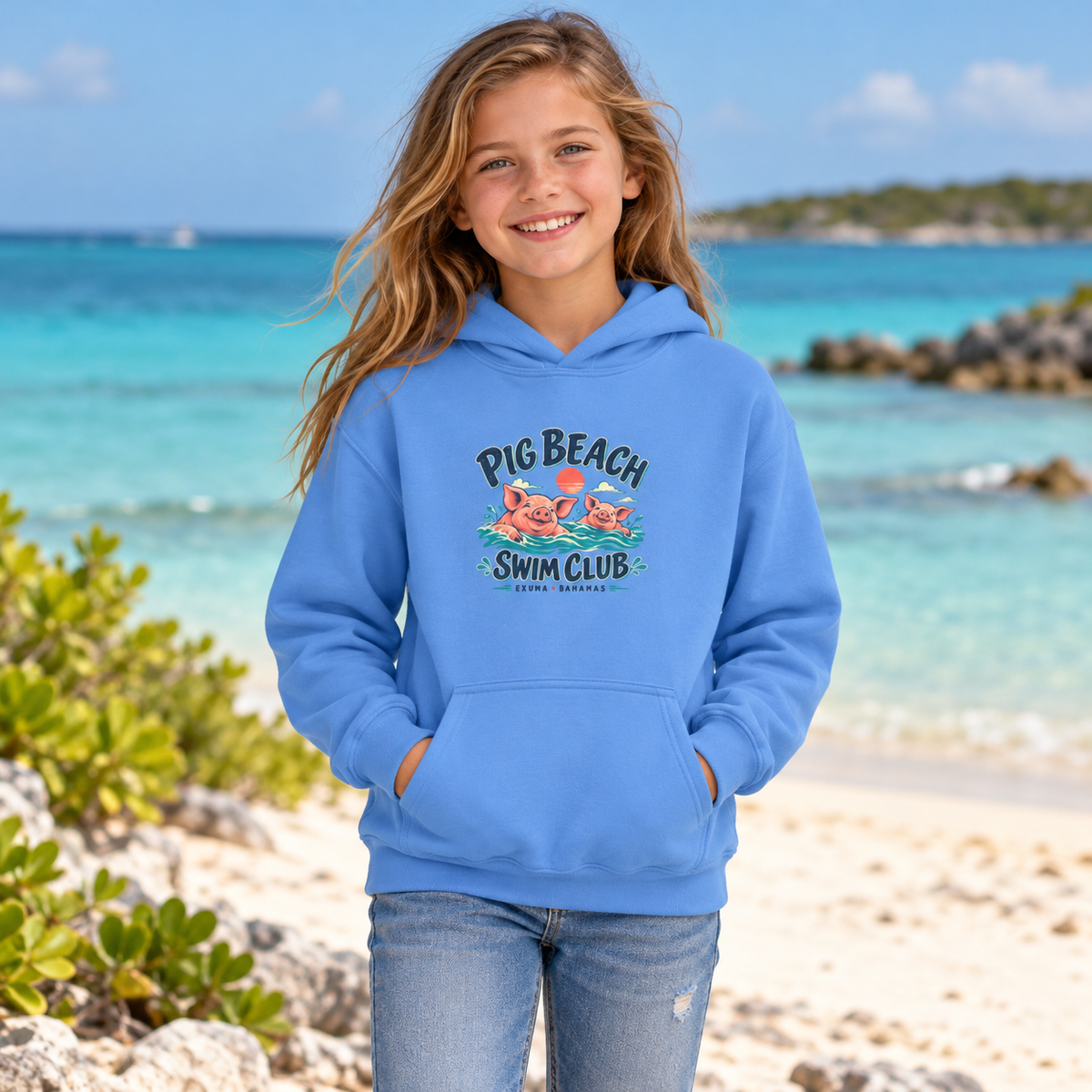 AI lifestyle mockup of a child wearing the Carolina Blue Pig Beach Swim Club Exuma Bahamas Gildan 18500B youth hoodie on a tropical coast.