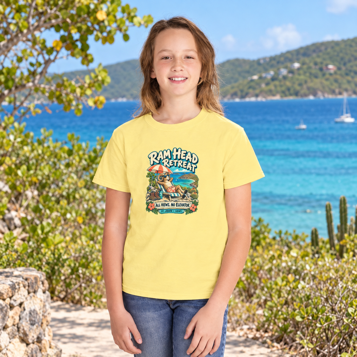 AI-generated youth lifestyle mockup of a child wearing a Butter Comfort Colors 9018 T-shirt with Ram Head Retreat artwork beside a tropical bay.