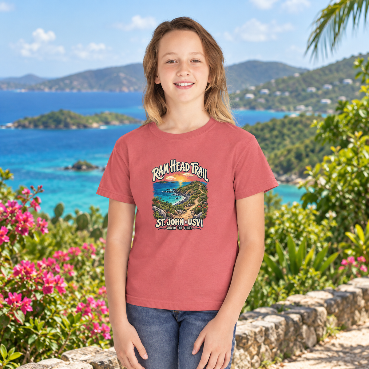 AI-generated lifestyle mockup of a child wearing a Watermelon Comfort Colors 9018 youth tee with Ram Head Trail St John USVI artwork by a tropical bay.